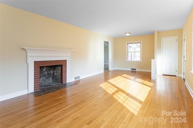 unfurnished living room with hardwood / wood-style floors and a brick fireplace