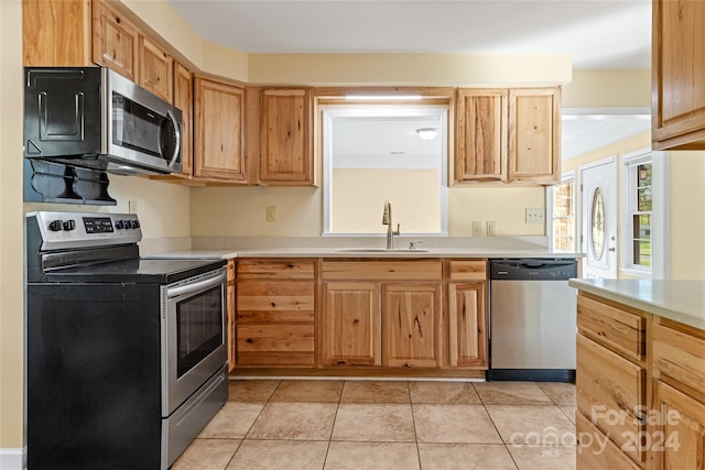 kitchen with sink, light tile patterned flooring, and stainless steel appliances