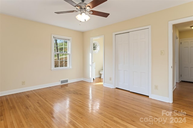 unfurnished bedroom featuring ceiling fan, light hardwood / wood-style floors, ensuite bathroom, and a closet