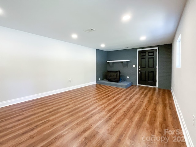 unfurnished living room featuring light wood-type flooring and a wood stove