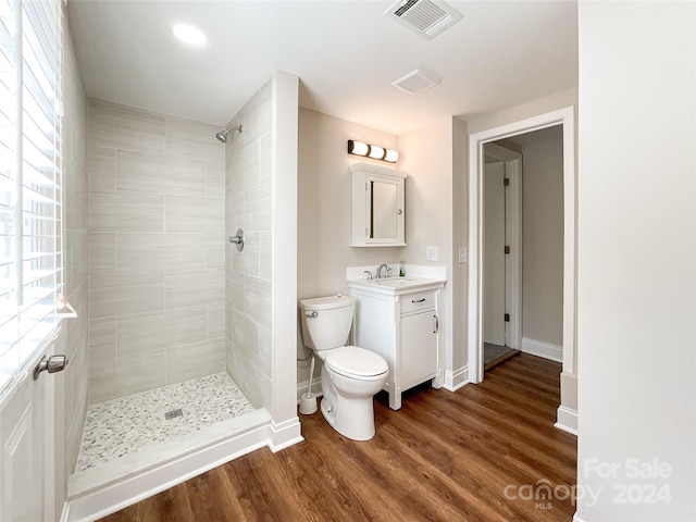 bathroom featuring vanity, hardwood / wood-style flooring, toilet, and tiled shower