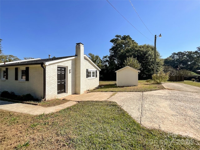 view of side of home featuring a storage shed and a yard