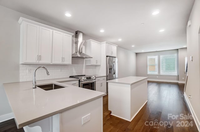 kitchen with stainless steel appliances, sink, wall chimney range hood, white cabinets, and a center island