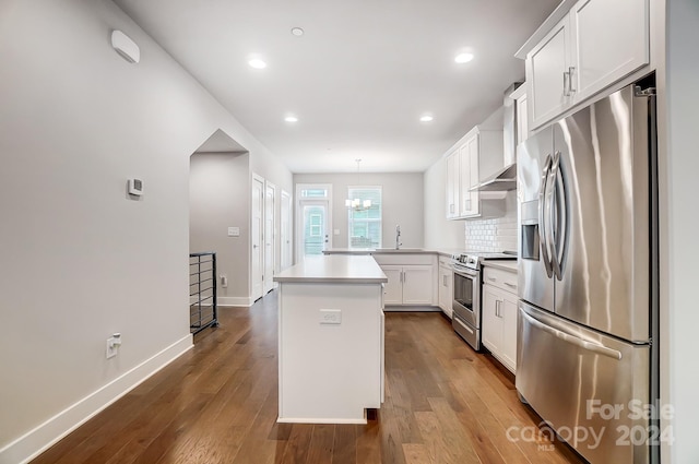 kitchen with pendant lighting, a center island, appliances with stainless steel finishes, tasteful backsplash, and white cabinetry