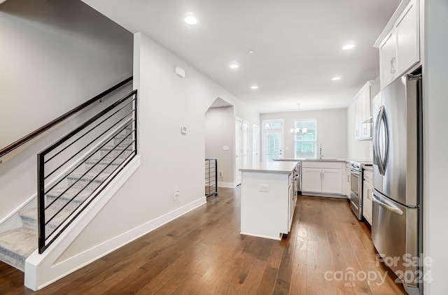 kitchen featuring a center island, wood-type flooring, white cabinetry, kitchen peninsula, and stainless steel appliances