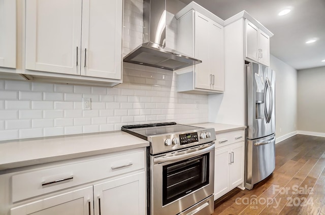 kitchen with white cabinetry, dark wood-type flooring, stainless steel appliances, and wall chimney range hood