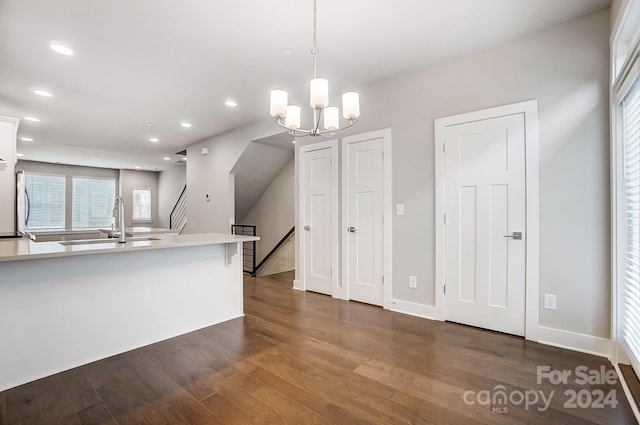 kitchen with refrigerator, dark wood-type flooring, sink, decorative light fixtures, and a notable chandelier