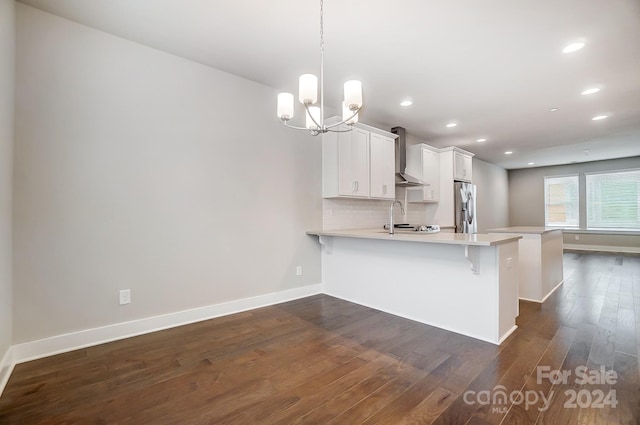 kitchen with pendant lighting, a breakfast bar, white cabinets, wall chimney range hood, and stainless steel fridge with ice dispenser