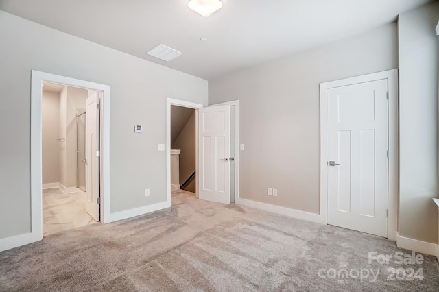 unfurnished bedroom featuring ensuite bathroom and light carpet