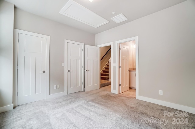 unfurnished bedroom with ensuite bathroom and light colored carpet