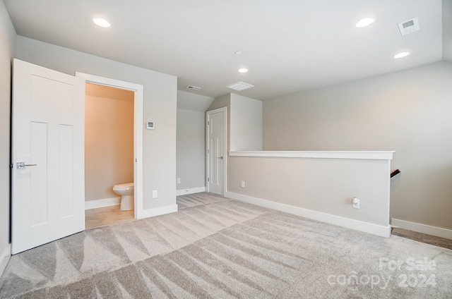 empty room with light colored carpet and lofted ceiling