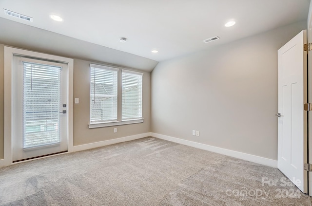 unfurnished room featuring light carpet and lofted ceiling