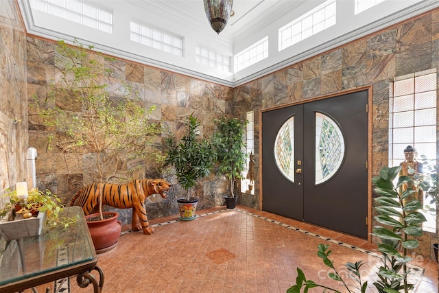 foyer with ornamental molding, a towering ceiling, and french doors