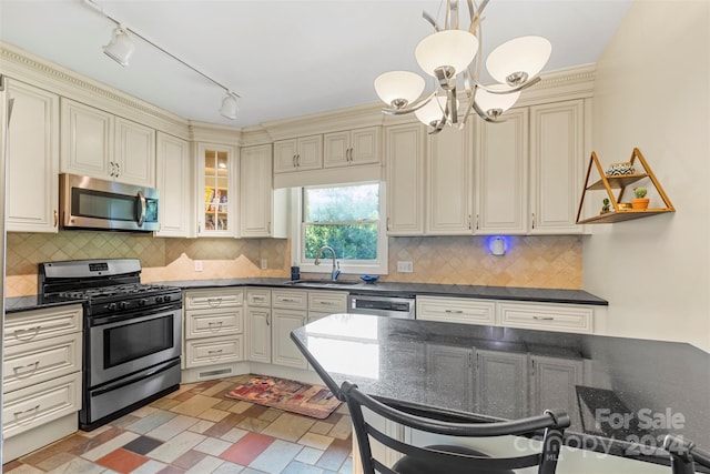 kitchen featuring backsplash, sink, hanging light fixtures, appliances with stainless steel finishes, and cream cabinets