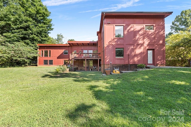 back of property featuring a deck and a lawn