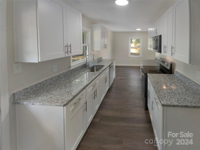 kitchen featuring appliances with stainless steel finishes, white cabinets, light stone counters, and sink