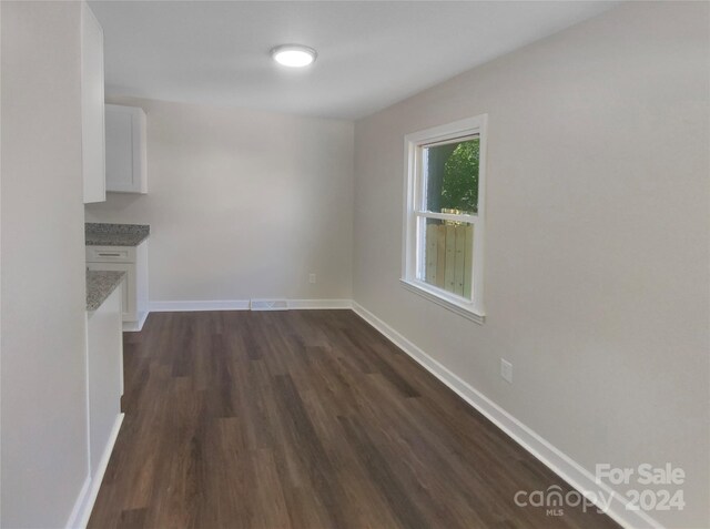 unfurnished dining area with dark wood-type flooring