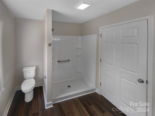 bathroom with toilet, a shower, and hardwood / wood-style flooring