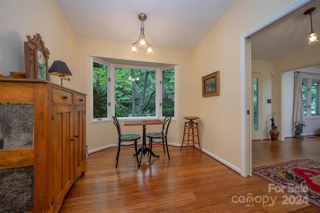 dining area with hardwood / wood-style flooring, lofted ceiling, and an inviting chandelier