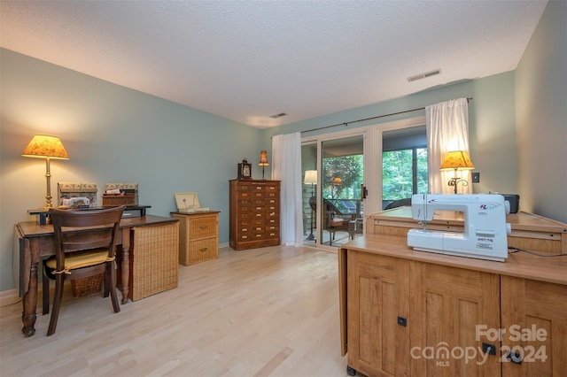 home office featuring a textured ceiling and light hardwood / wood-style flooring