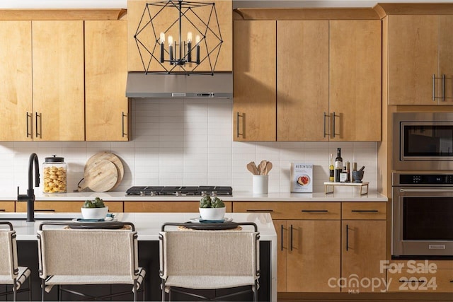 kitchen featuring a chandelier, pendant lighting, stainless steel appliances, and tasteful backsplash