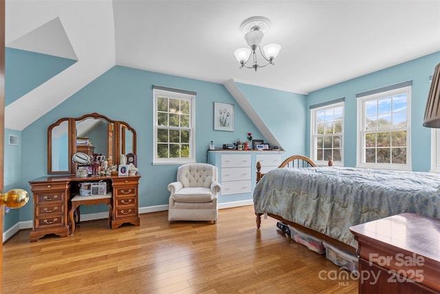 bedroom with light hardwood / wood-style floors, lofted ceiling, and an inviting chandelier