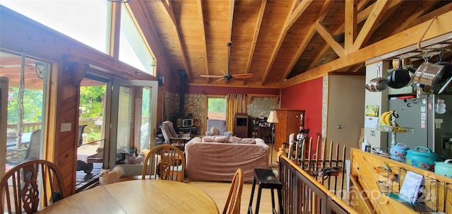 interior space with ceiling fan, a wood stove, vaulted ceiling with beams, and wooden ceiling