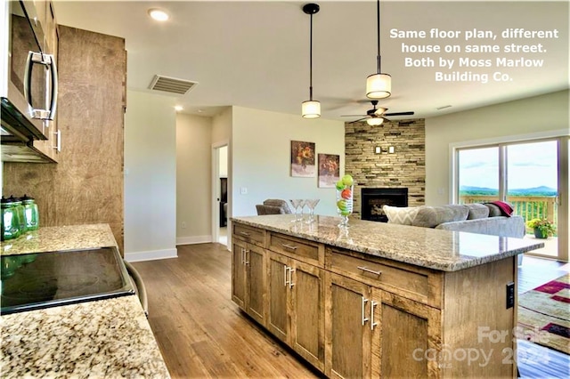 kitchen featuring a center island, stove, hanging light fixtures, light hardwood / wood-style flooring, and a fireplace