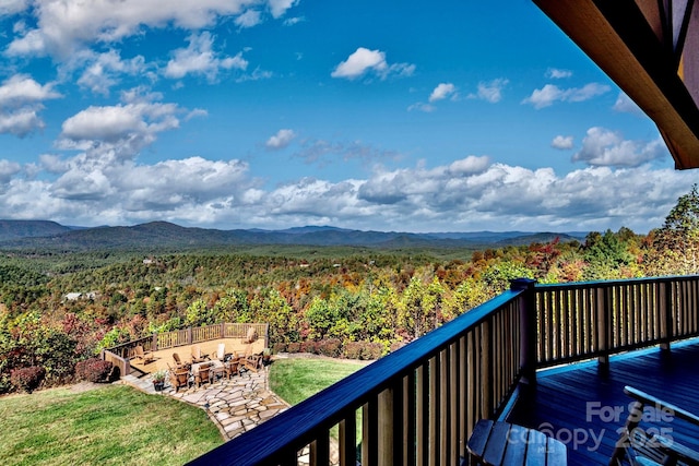 balcony with a mountain view, a fire pit, and a view of trees