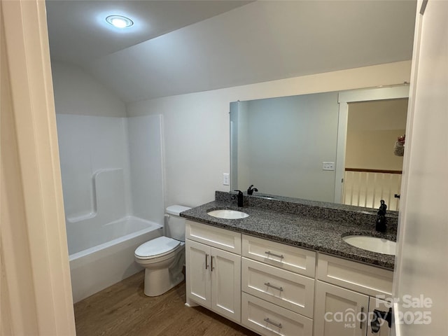 full bath with a sink, lofted ceiling, wood finished floors, and double vanity