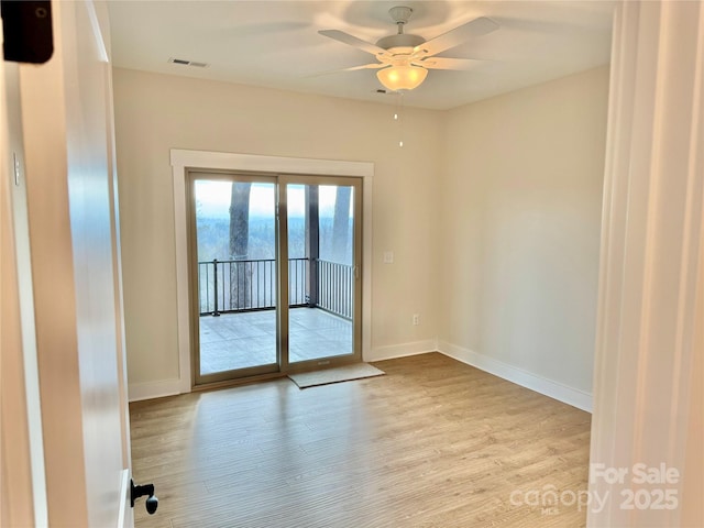 spare room featuring visible vents, baseboards, wood finished floors, and a ceiling fan