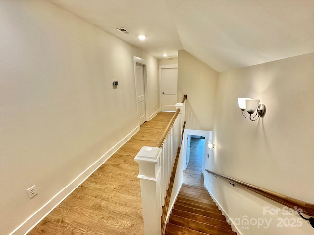 stairway featuring lofted ceiling, baseboards, and wood finished floors