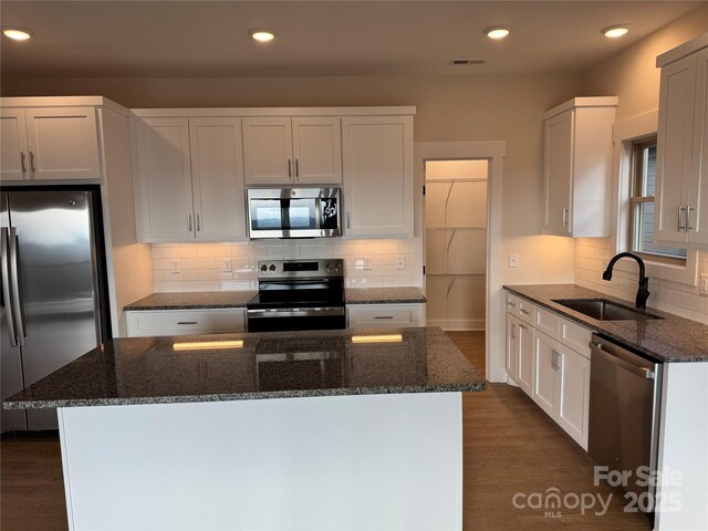 kitchen with visible vents, appliances with stainless steel finishes, dark stone counters, and a sink