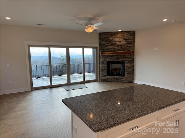 kitchen with visible vents, ceiling fan, open floor plan, dark stone counters, and white cabinetry