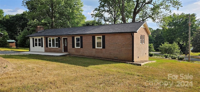 ranch-style home with a front lawn and a patio area