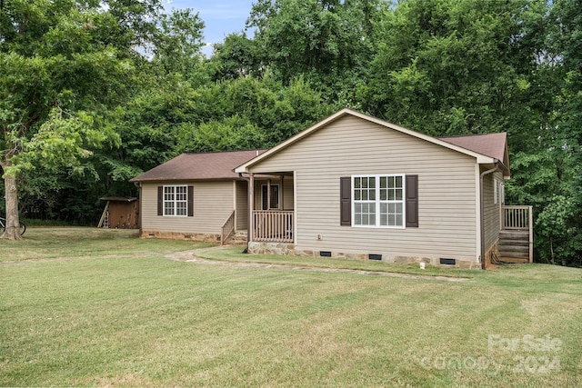 ranch-style house featuring covered porch and a front lawn