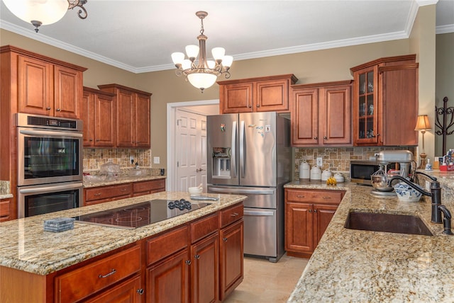 kitchen with appliances with stainless steel finishes, a notable chandelier, pendant lighting, light stone counters, and sink