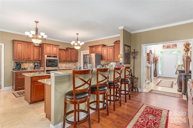 kitchen featuring stainless steel appliances, decorative light fixtures, an inviting chandelier, a center island, and tasteful backsplash