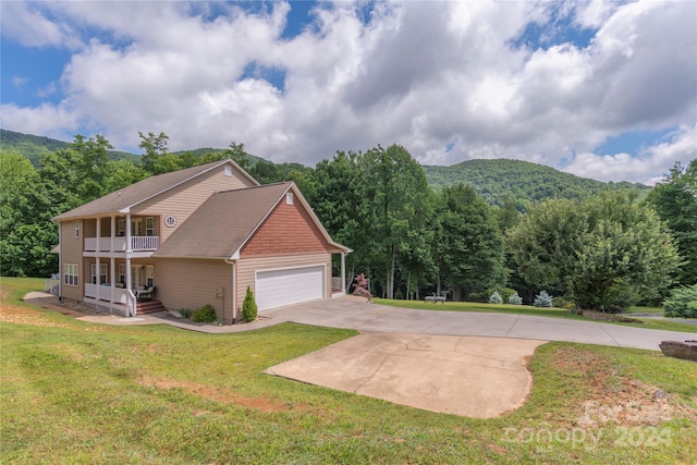 view of front of property featuring a front lawn, a mountain view, a balcony, a porch, and a garage