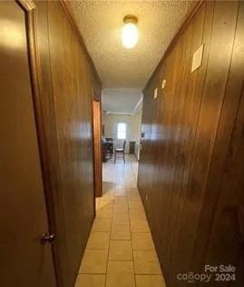 hall featuring light tile patterned flooring and wood walls