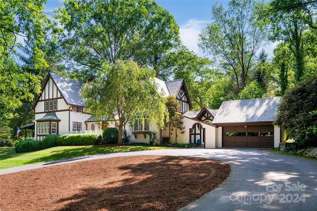 tudor-style house featuring a garage and a front lawn