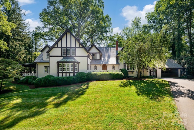 tudor-style house featuring a front lawn and a carport