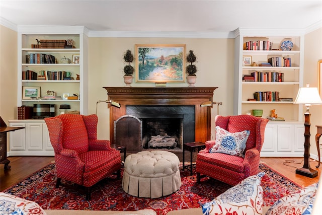 living area with a fireplace, crown molding, wood-type flooring, and built in shelves