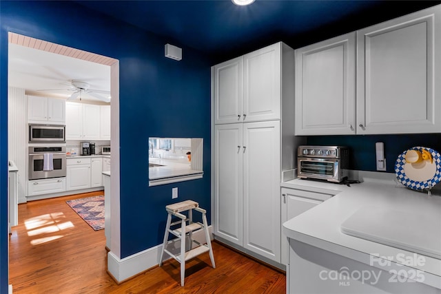 kitchen featuring ceiling fan, stainless steel appliances, light hardwood / wood-style floors, and white cabinets