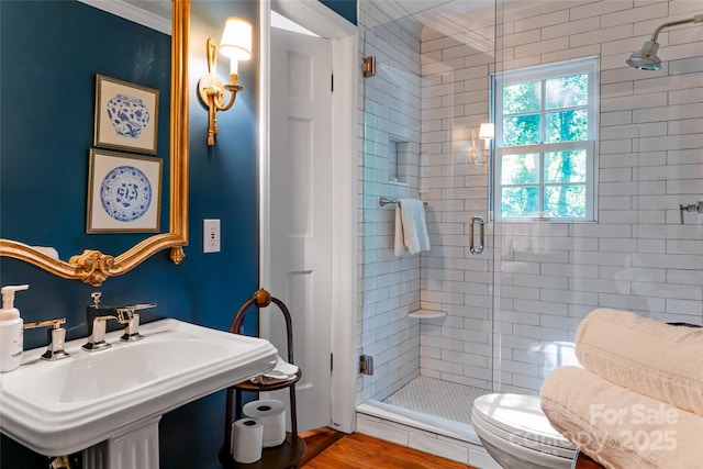 bathroom featuring toilet, sink, a shower with door, and hardwood / wood-style floors