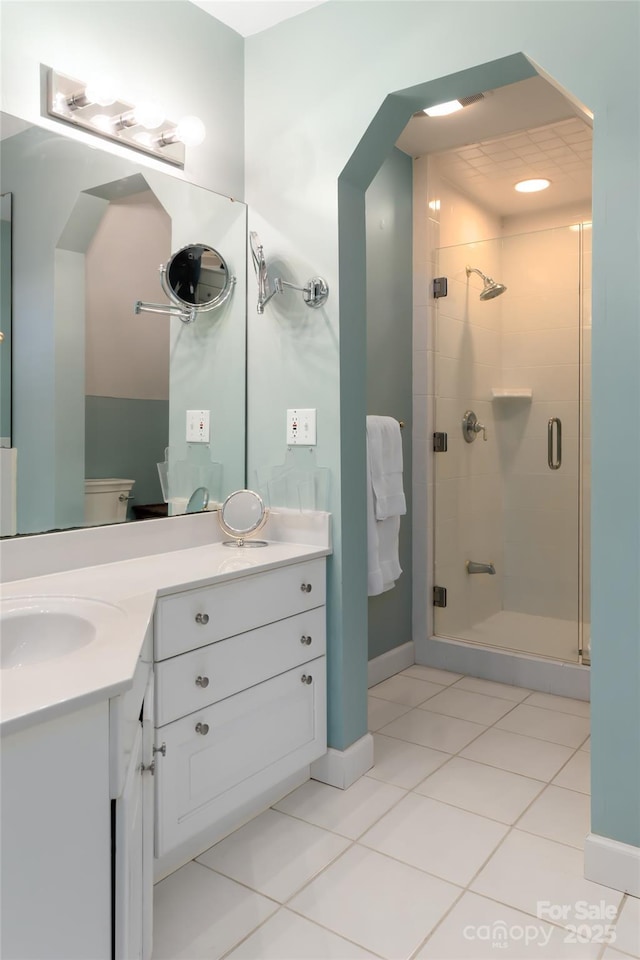 bathroom featuring tile patterned flooring, vanity, an enclosed shower, and toilet