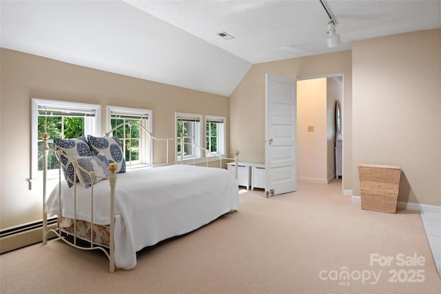 carpeted bedroom with vaulted ceiling, a baseboard radiator, and track lighting