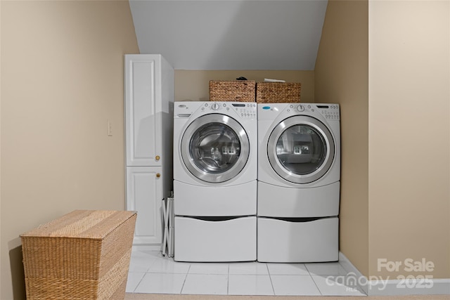 clothes washing area with cabinets, washing machine and clothes dryer, and light tile patterned floors