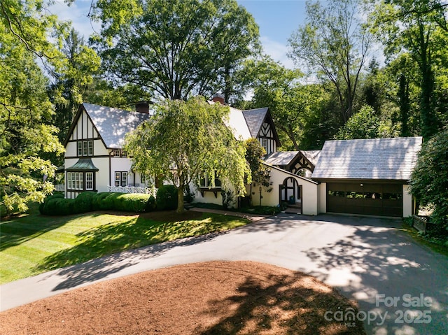 tudor-style house featuring a garage and a front lawn