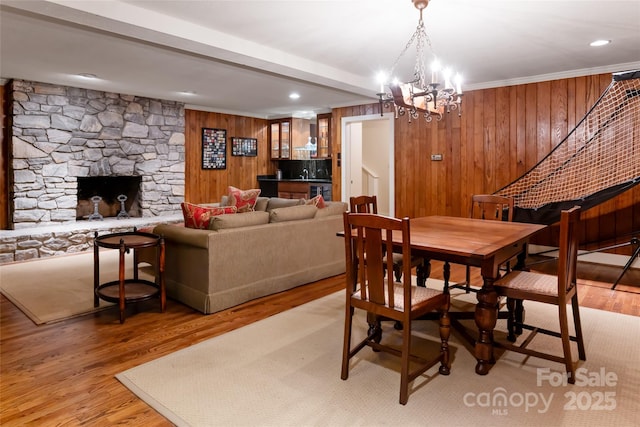 dining area with crown molding, wooden walls, a fireplace, and light hardwood / wood-style floors